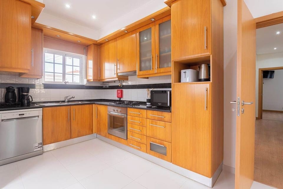 Modern kitchen with wooden cabinetry and black countertops — Villa Sol e Mar, holiday villa in Charneca da Caparica