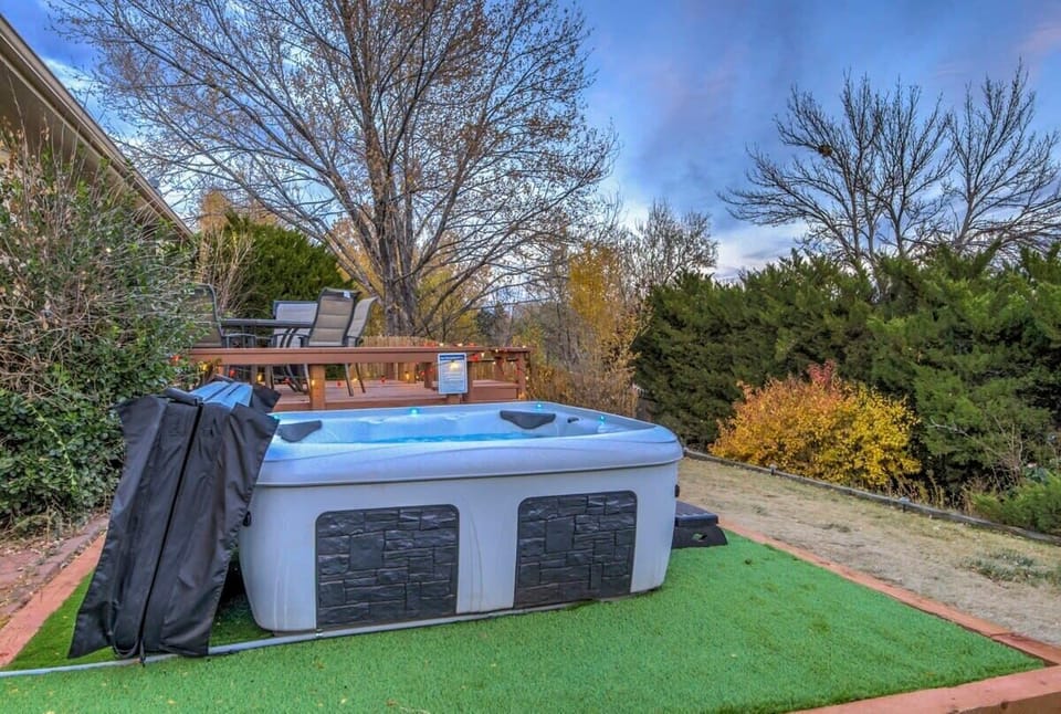 Backyard hot tub set on a tidy turf pad—sink in for a steamy soak while trees frame the sky, then step out to fresh air and quiet surroundings.