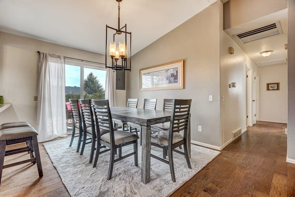 Big-table dining made for together time—spread out with plenty of high-back chairs for meals or cards, then follow the warm wood floors down the hall as soft lighting keeps the vibe relaxed.