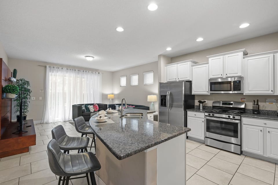 Fully equipped kitchen with a counter, 5 barstools, and a sink.