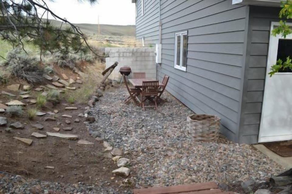 Outdoor dining area to the side of the guesthouse with seating and charcoal grill.