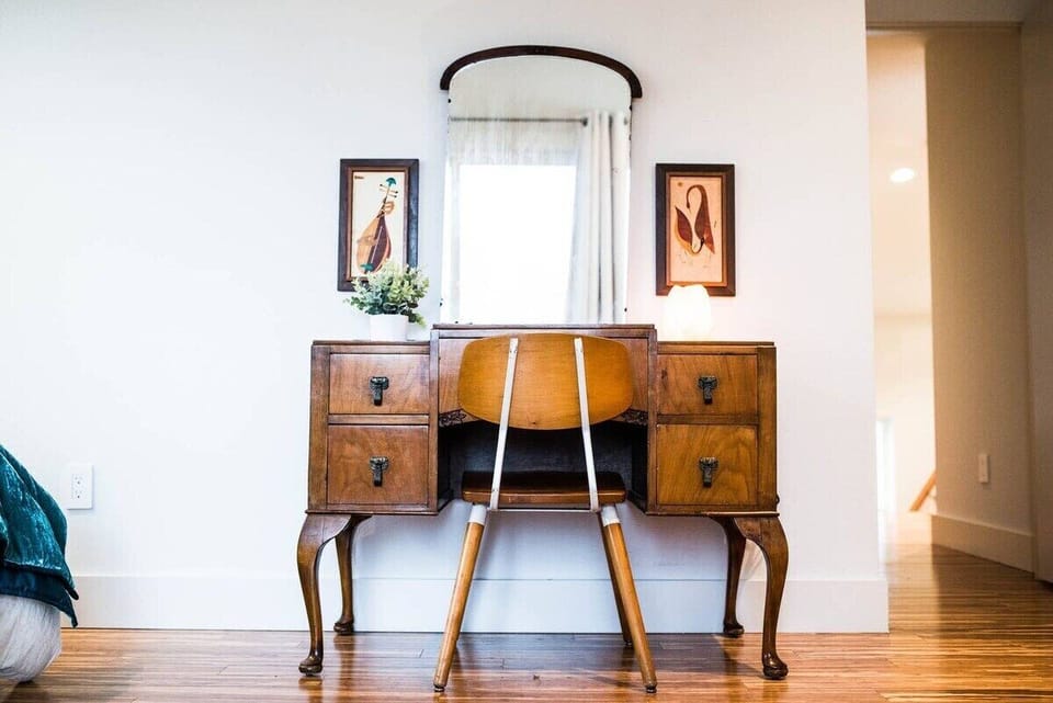 A King bedroom with tons of space, this room features a sweet vintage vanity, a chest of drawers, and a small reading chair in opposite corner.