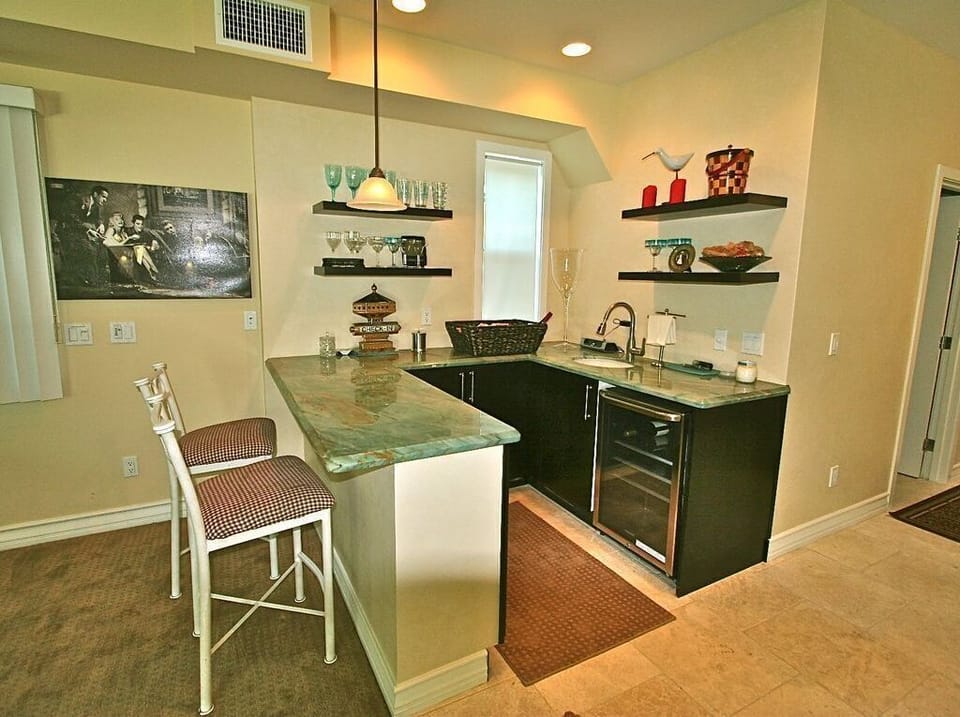 Downstairs bar with wine fridge next to large screen tv and pool table