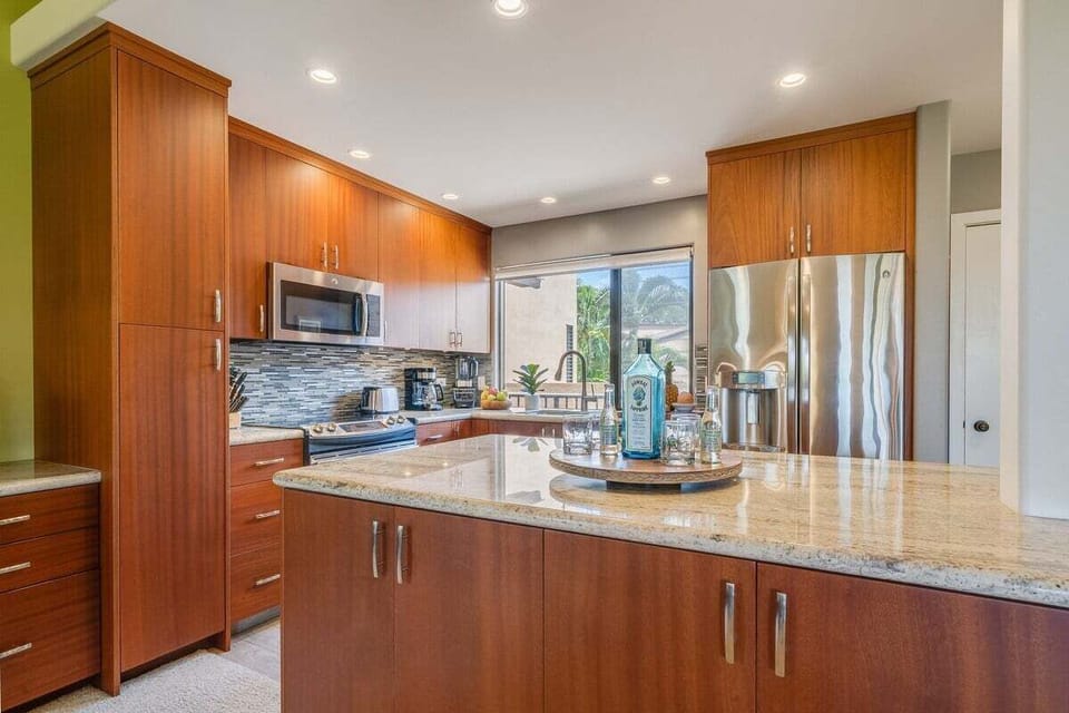 Granite islands anchor the kitchen, wood and steel blending into a modern calm.