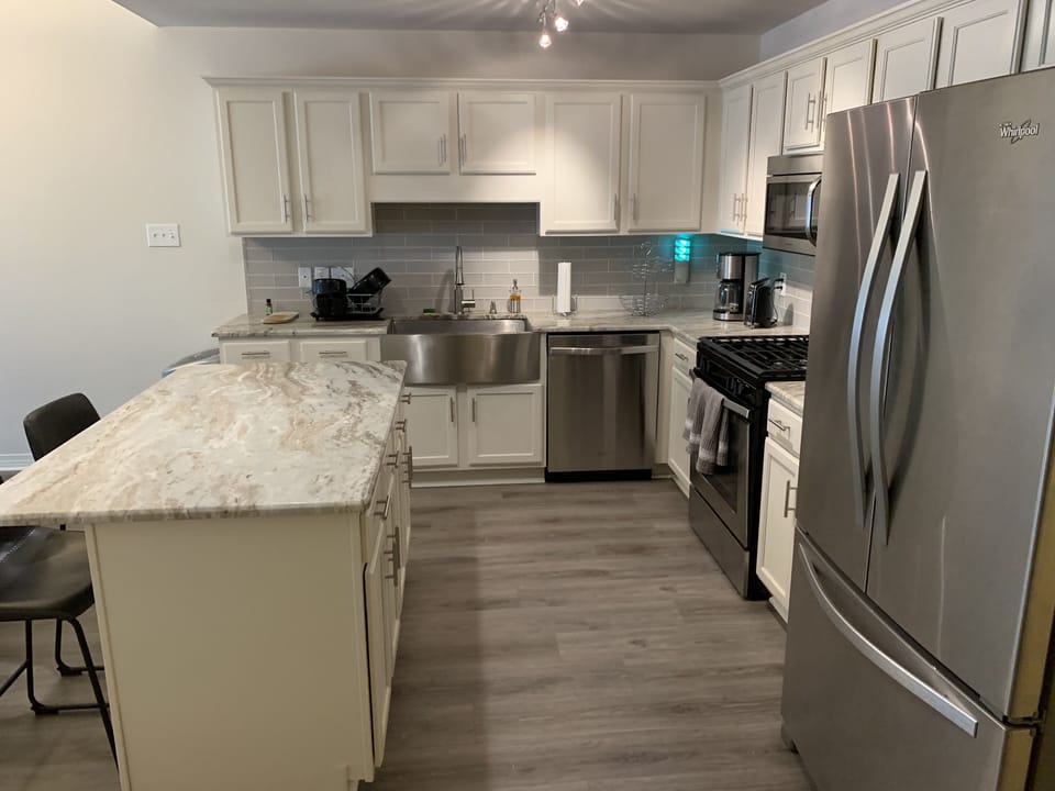 Refrigerator with ice maker, stainless farmhouse sink, glass tile backsplash