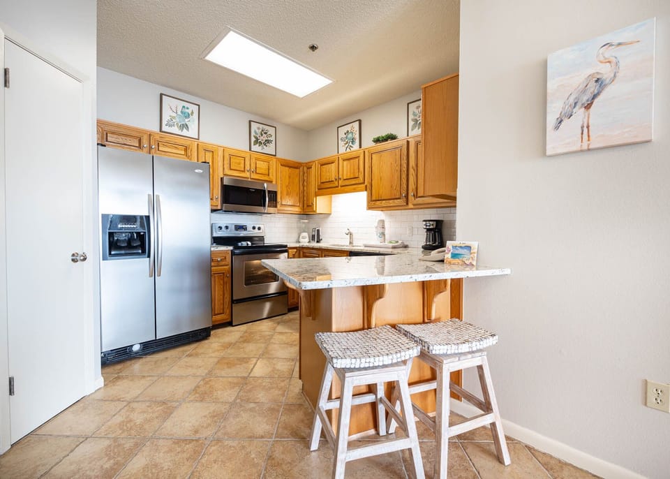 Cook and gather at the inviting kitchen with stainless appliances, warm wooden cabinetry, and granite countertops