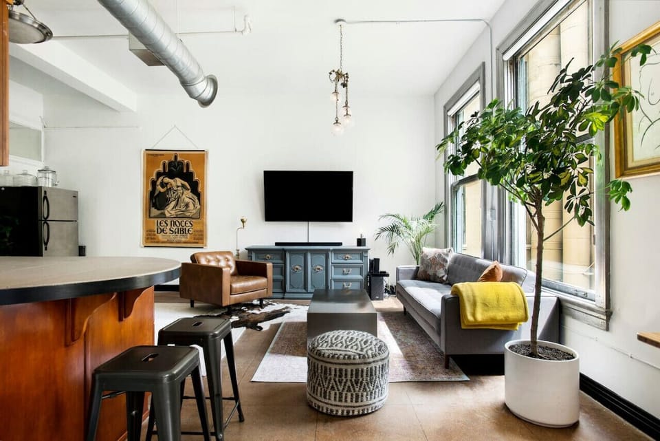 A thoughtfully designed space featuring a cozy sofa, large windows, natural light, and a cozy ambiance for ultimate comfort.
