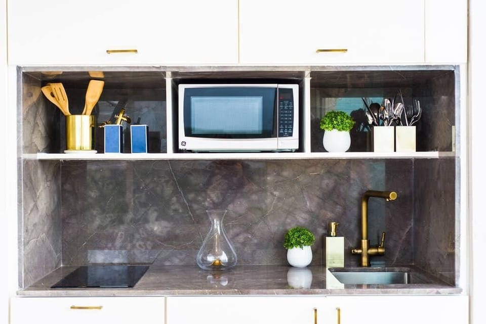 Kitchenette with stove, sink, mini fridge, microwave, and Nespresso machine. (2)