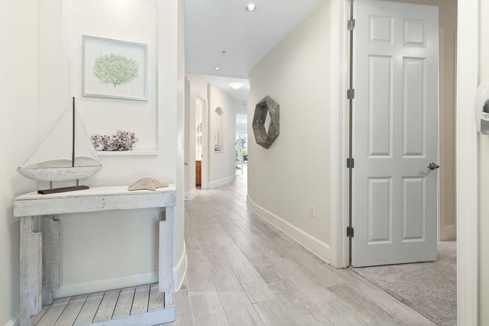 Step inside your serene coastal retreat, where whitewashed wood and nautical touches welcome you into a peaceful haven. The light-filled hallway invites you to unwind and discover your home away from home.