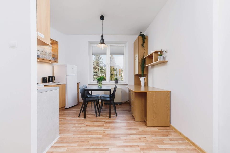 A white hallway leading into a kitchen, with wooden flooring and a small open closet area visible in the background.