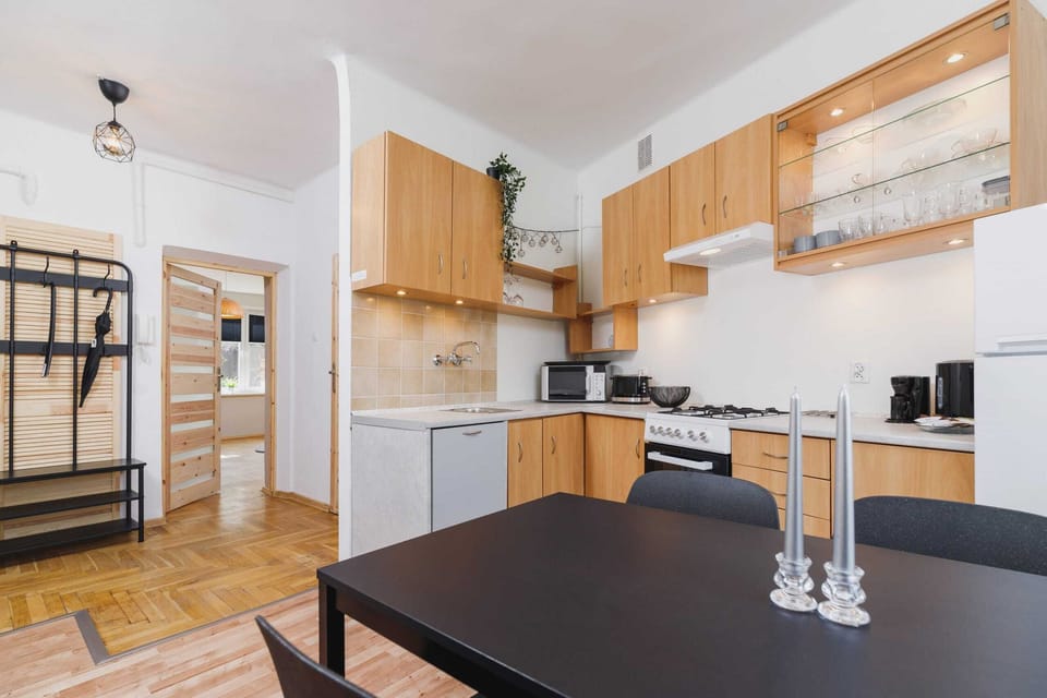 A dining area with a black table and four chairs, placed next to a wood-finished kitchen. 