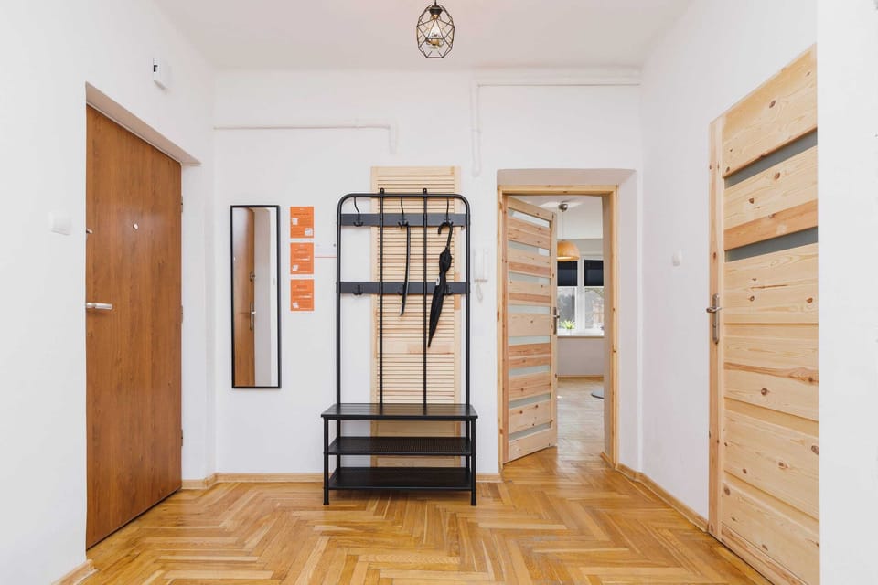 A view of a hallway leading to a wooden wardrobe and door. The area is brightly lit with overhead lighting.