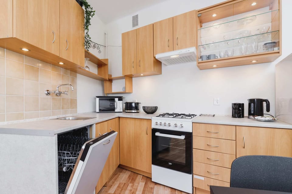 A kitchen with wooden cabinets, a white backsplash, a stove, and a microwave. The space feels warm and functional.