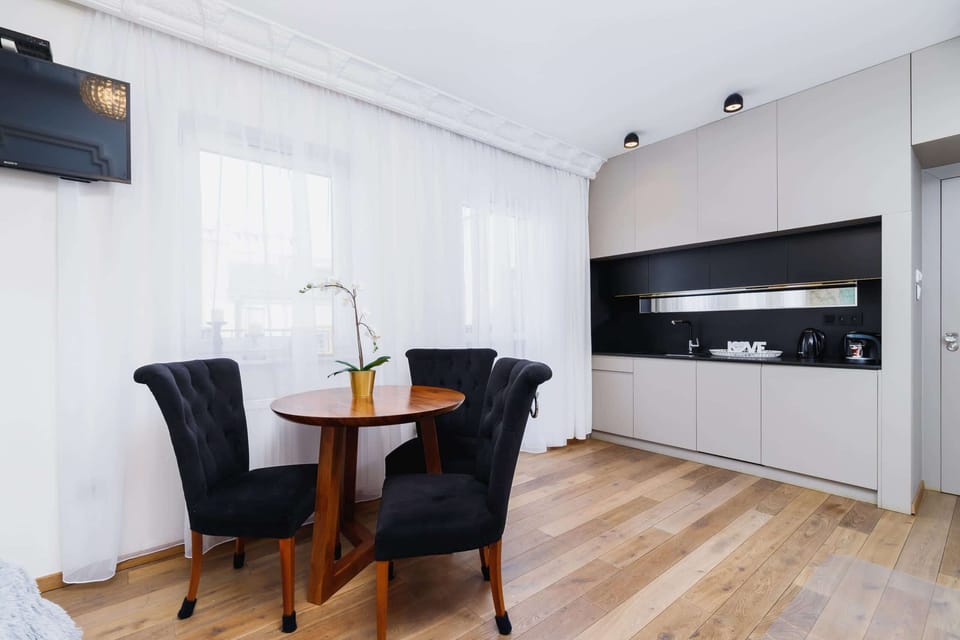 A modern dining area with a small round table, chairs, and a window allowing natural light.
