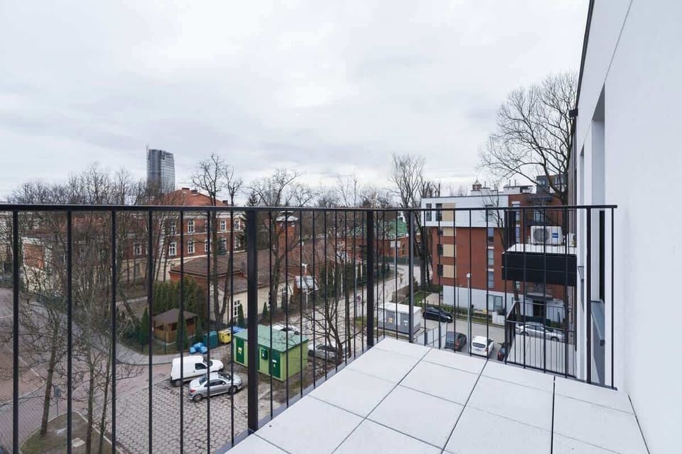 An outdoor balcony offering a view of the surrounding cityscape, with modern railings and a small outdoor space.