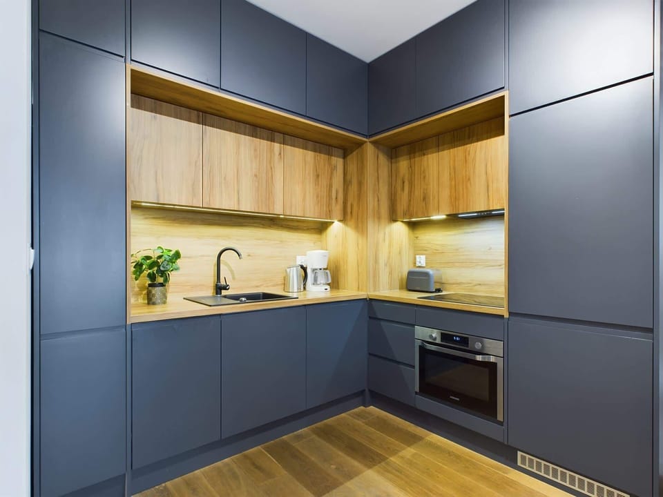 A kitchenette featuring blue cabinets and wooden countertops, combining a bold color choice with natural accents.