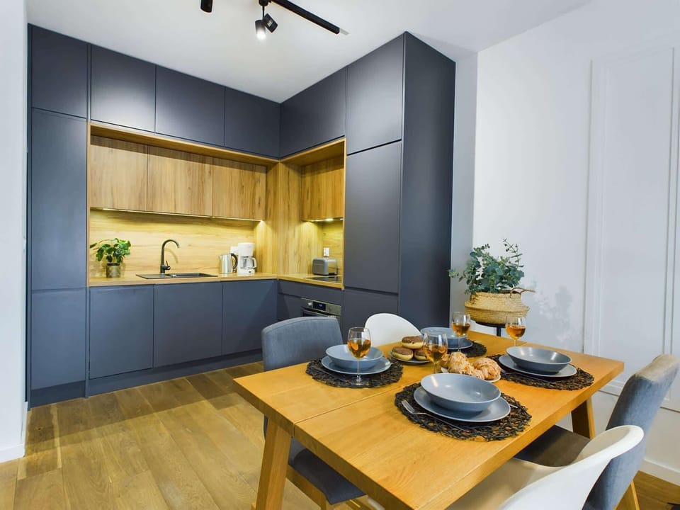 A dining area featuring a wooden table and chairs, neatly set up for dining with modern lighting above.