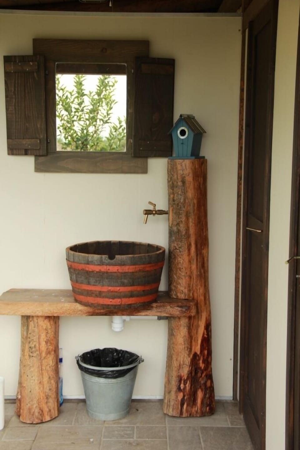 Wooden sink and mirror in front of toilette and shower.