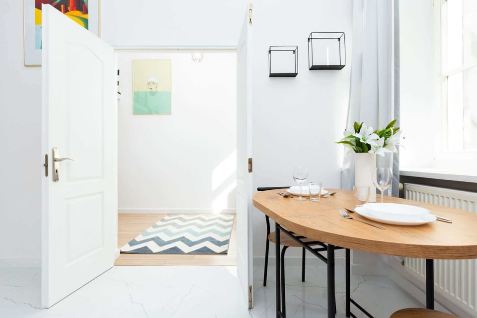 A dining space with a large window, white walls, and minimalist furniture, combining simplicity and elegance.