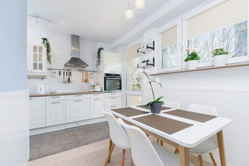 A dining area adjoining the kitchen, featuring a table and chairs, with windows letting in plenty of natural light.