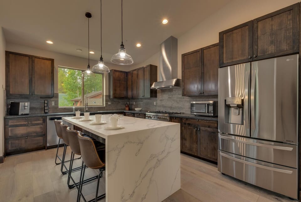 - Modern kitchen with island seating and bar stools  
- Stainless steel appliances and sleek stone accents  
- Fully equipped cabin kitchen for family gatherings