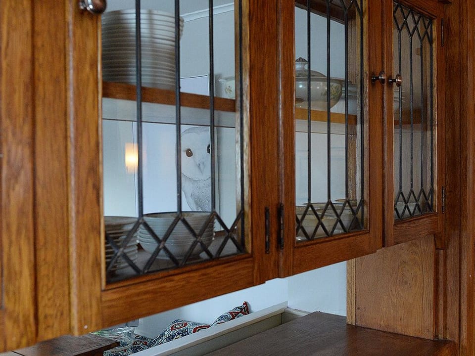 Original glass front cabinets above the pass through to the kitchen 