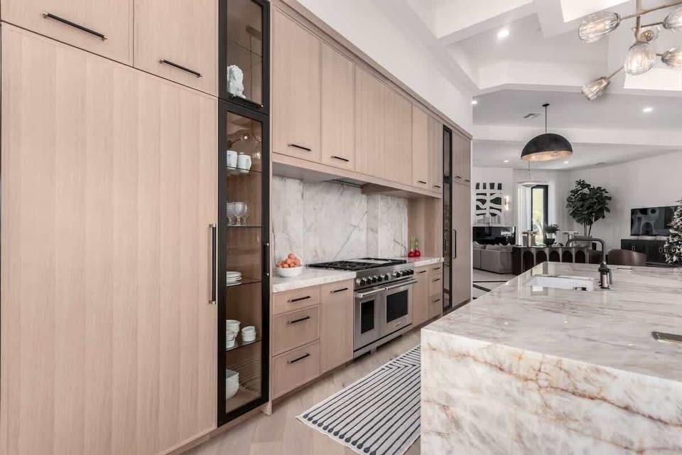 Main kitchen area with stainless steel appliances, 2 kitchen islands, a dining area, and access to the backyard.