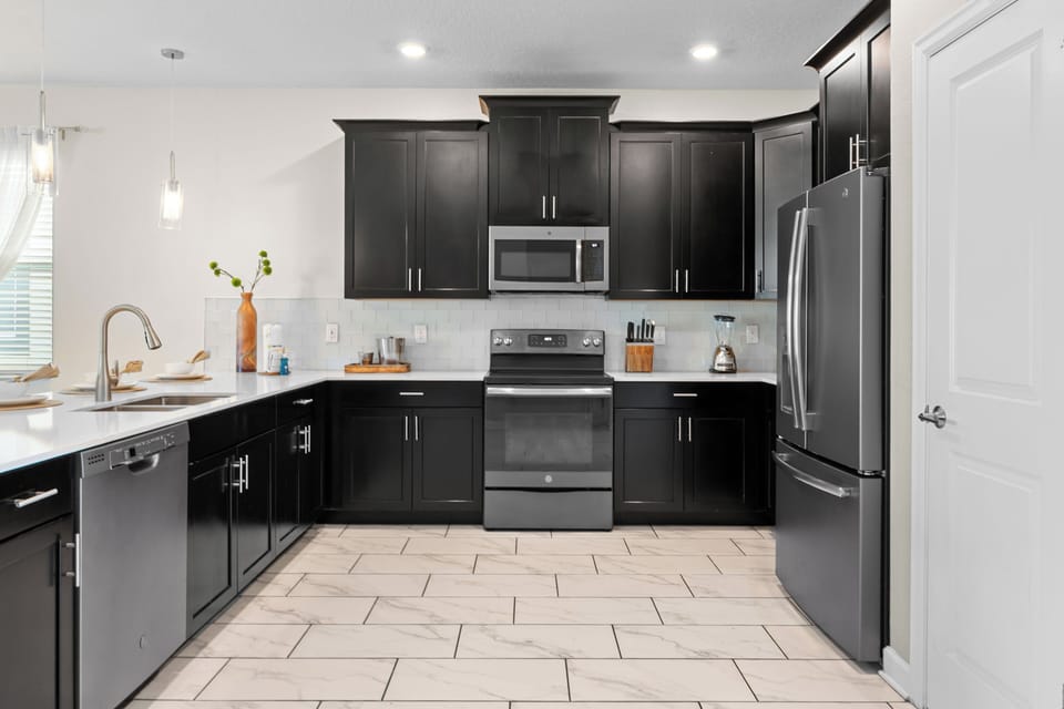 Your modern kitchen features sleek black cabinets, stainless steel appliances, and pristine white countertops - perfect for creating memorable meals.