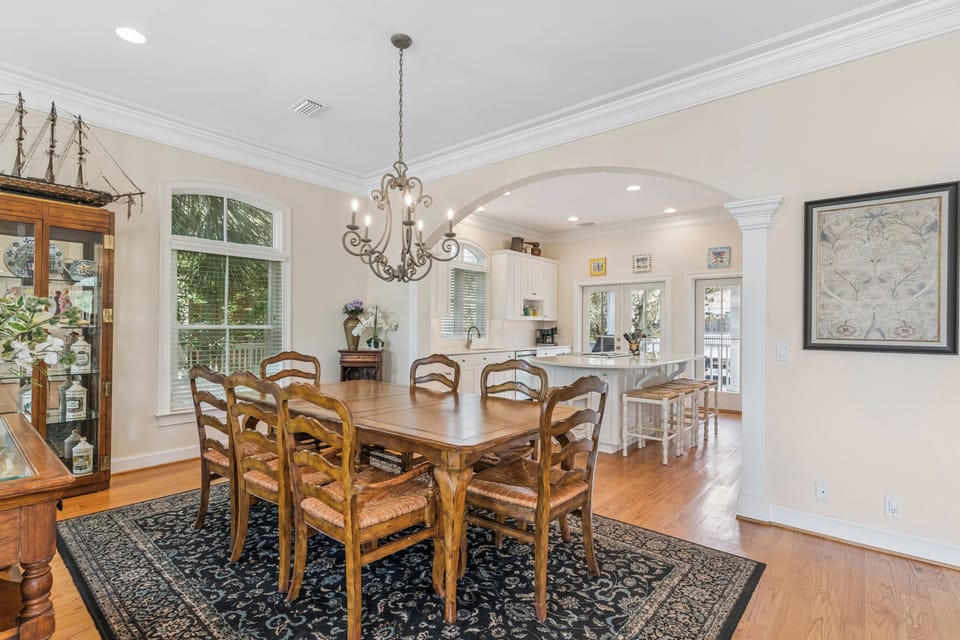 Your open-concept dining and kitchen area flows seamlessly together, bathed in natural light from arched windows and French doors. Gather around the warm wood table or perch at the island for morning coffee.