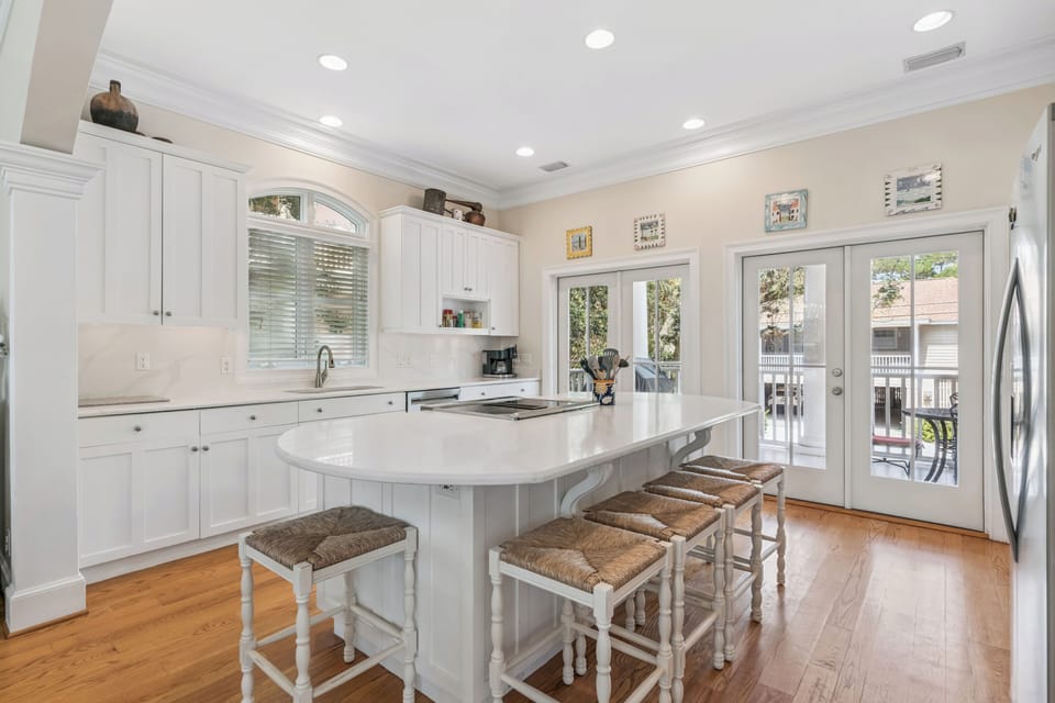 Gather around the bright island for morning coffee or meal prep, with French doors opening to your private balcony and warm wood floors underfoot.