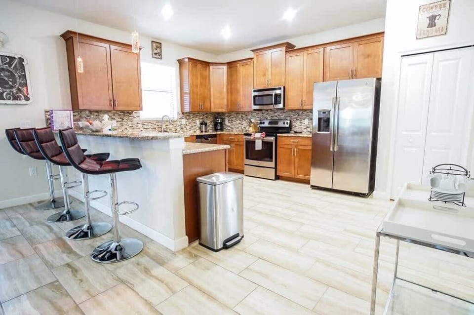 Large fully-equipped kitchen with a bar countertop and four barstools.
