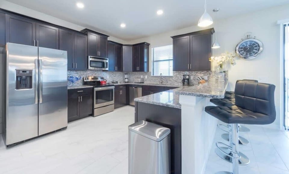 Fully-equipped kitchen with a bar countertop and four barstools.