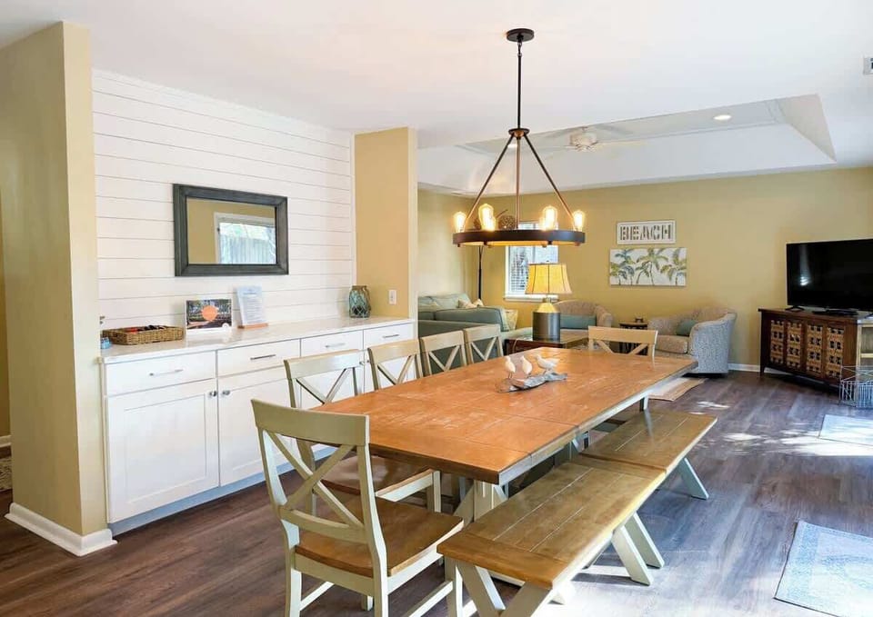 Spacious dining area with a large wooden table and modern lighting for family gatherings.