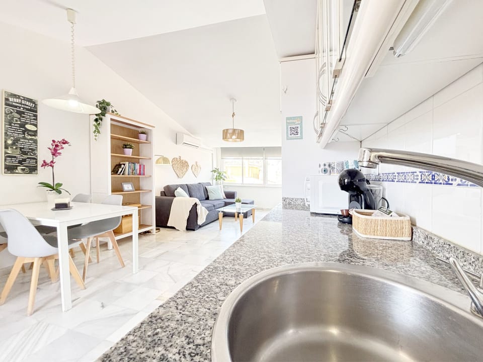 Open-plan space seamlessly connecting the kitchen with a granite countertop, a minimalist dining area, and a designer sofa living room. Maximum brightness and quality finishes.