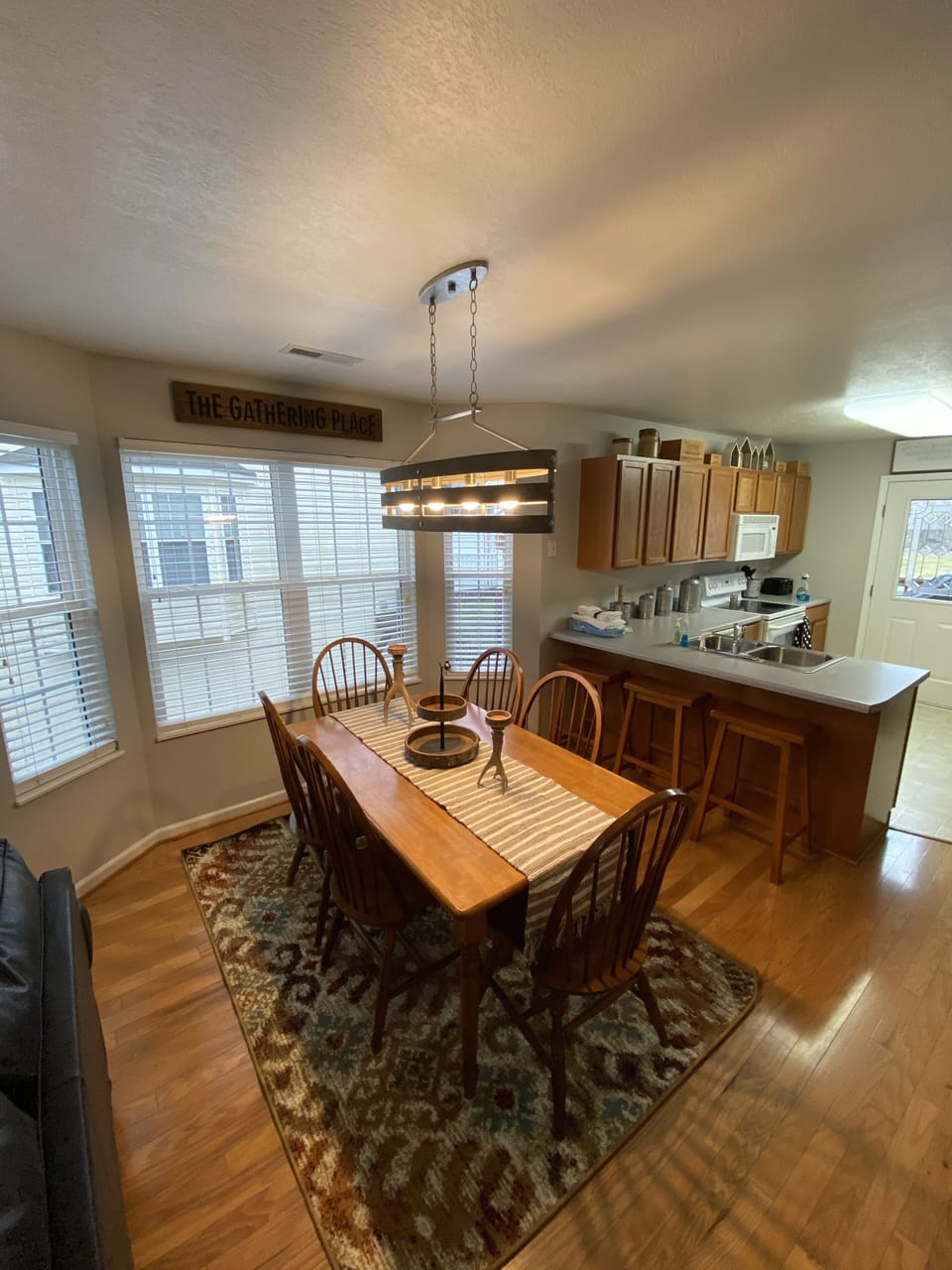 Dining area with plenty of seating beside bar with 3 stools for extra seating. 