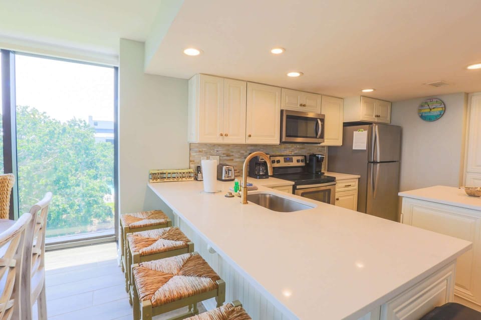 The kitchen features a tiled backsplash, white cabinets and stainless steel appliances.