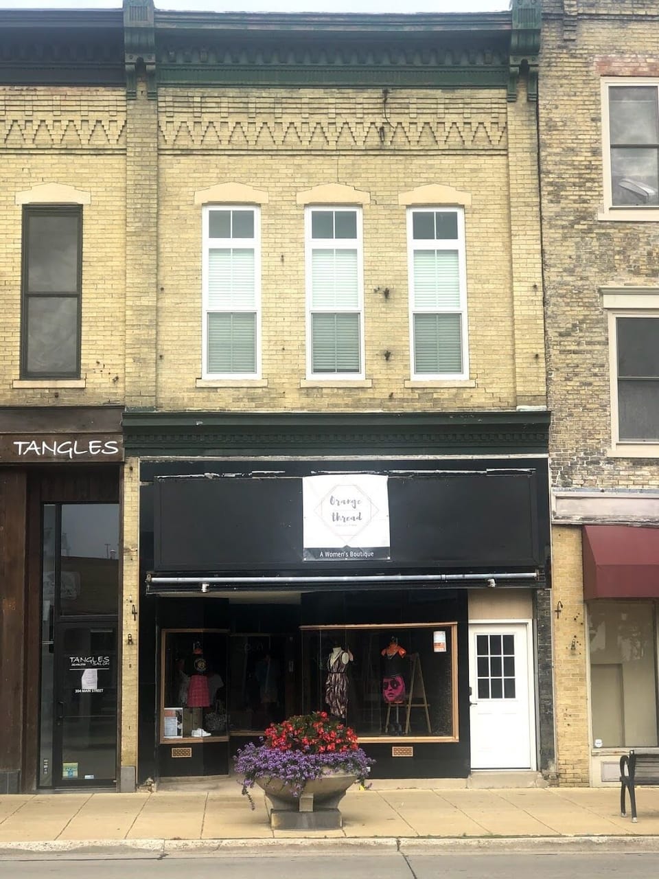 Enter through the white door just right of the retail space. 