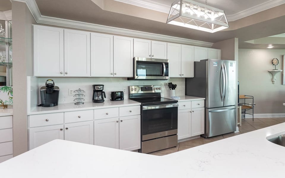 Prepare meals in this kitchen with elegant lighting, stainless appliances, spacious countertops, and coffee corner
