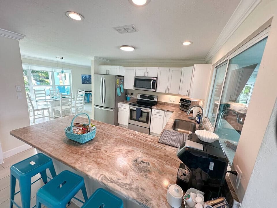 Kitchen with bar seating for 4 with plenty of coffee options, including a normal carafe, k-cup, pour over coffee, French press and electric kettle