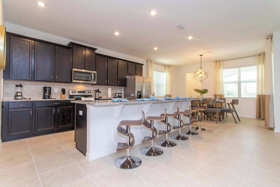 Chef-ready kitchen with rich espresso cabinets, a granite island seating 6, and stainless appliances. Open to the bright dining area for effortless meals together.