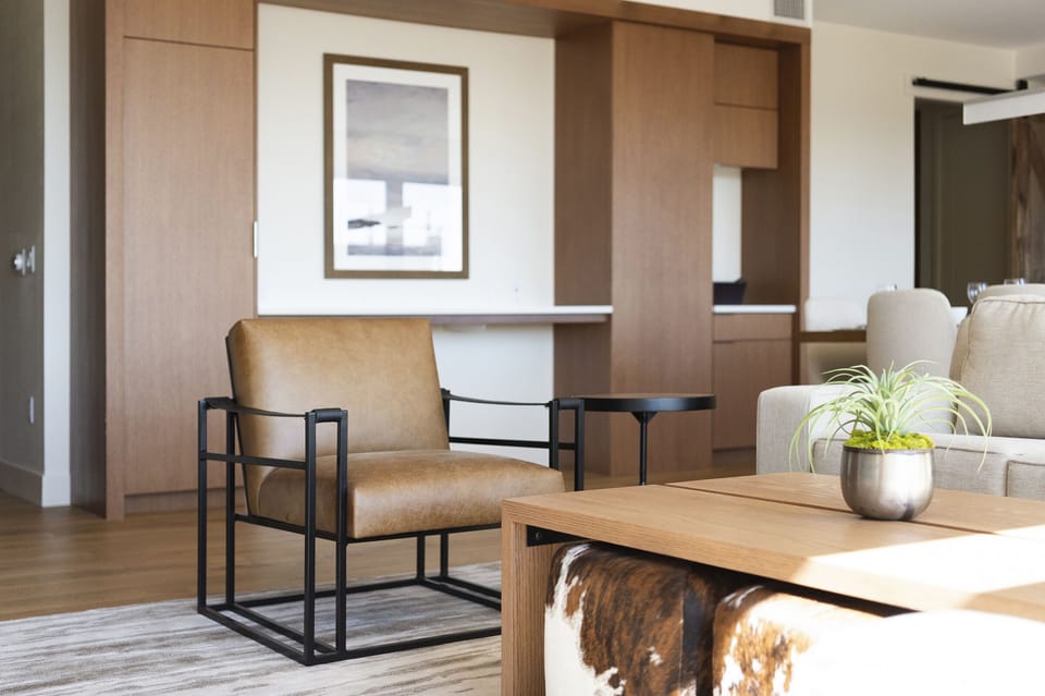 Unique modern mountain design, leather and iron accent chair in the living room, wooden coffee table, and cowhide cube poufs