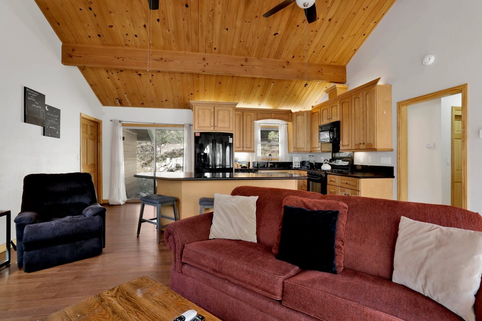 Cozy mountain living room with a stone fireplace, comfy seating, and smart TV—perfect for relaxing evenings, movie nights, and warm cabin vibes after outdoor adventures.