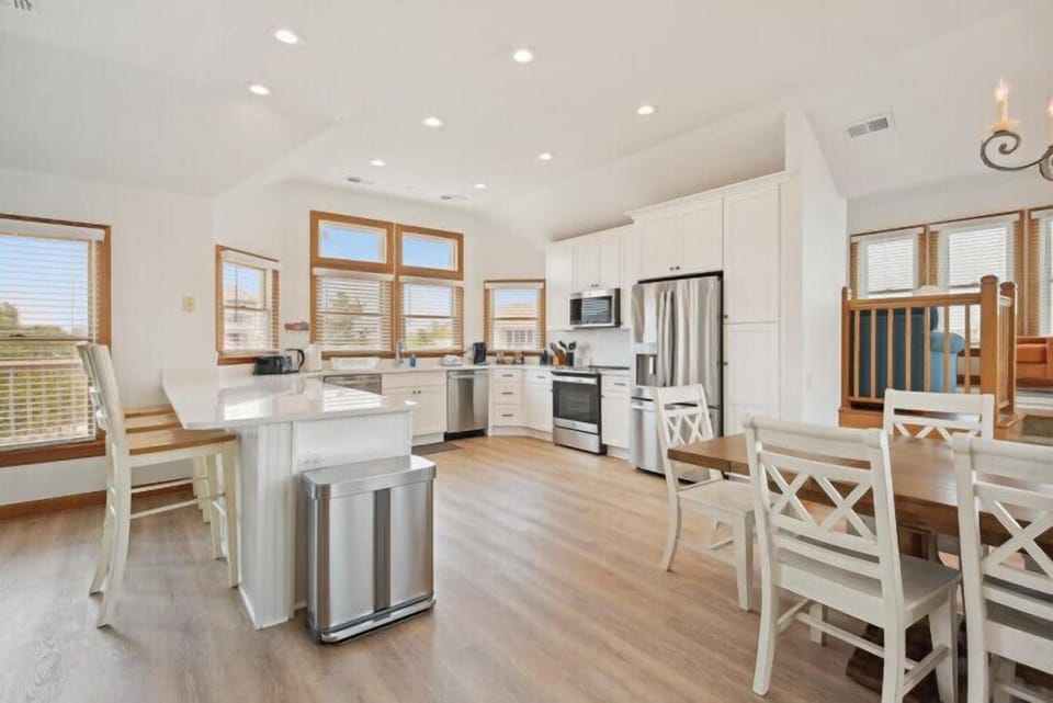 Step into your bright, airy kitchen where natural light pours in through stunning windows. You'll love preparing meals with modern stainless steel appliances and white cabinetry, while your family gathers at the inviting island or dining table.
