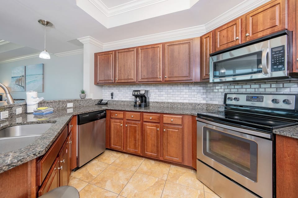 Modern kitchen featuring stainless appliances, granite countertops, coffee station, and stylish cabinetry