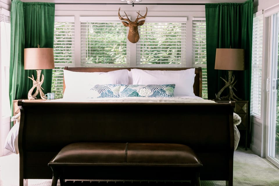 King bedroom is surrounded by two sliding glass doors in a sea of rhododendrons.