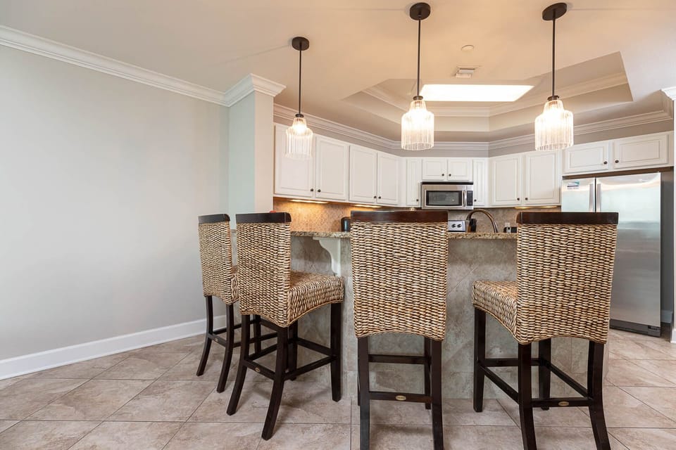 This kitchen features stylish bar seating, stainless appliances, and elegant pendant lighting, perfect for casual dining