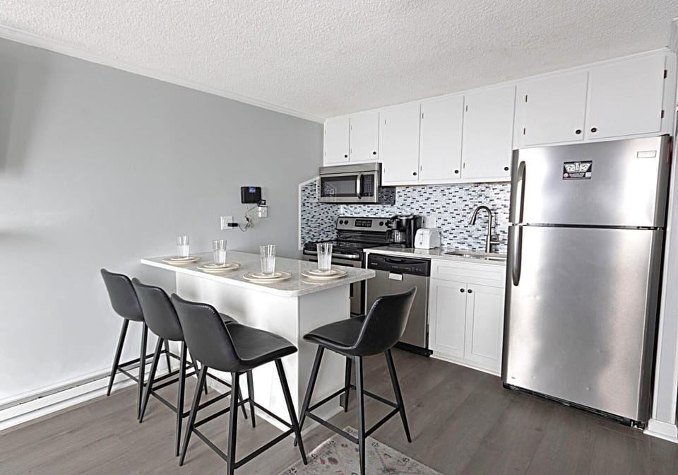 The modern kitchen has stainless steel appliances and a backsplash.