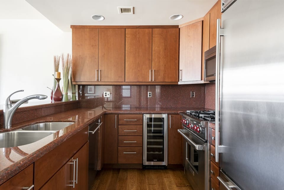 Fully equipped kitchen with stainless steel appliances, red granite countertops, and dark cherry wood cabinets