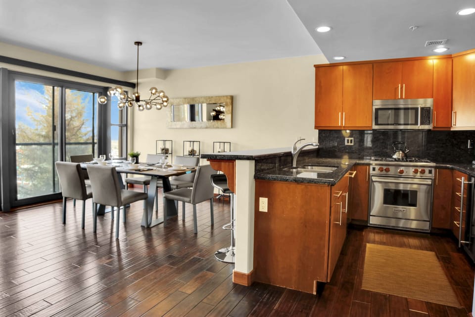 Lowell 304's open concept kitchen and dining area with hard wood floors throughout, creamy walls and mirror on the wall.