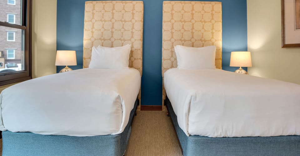 Lowell 304's second bedroom with two twin beds that have a large upholstered headboard and blue accent wall.